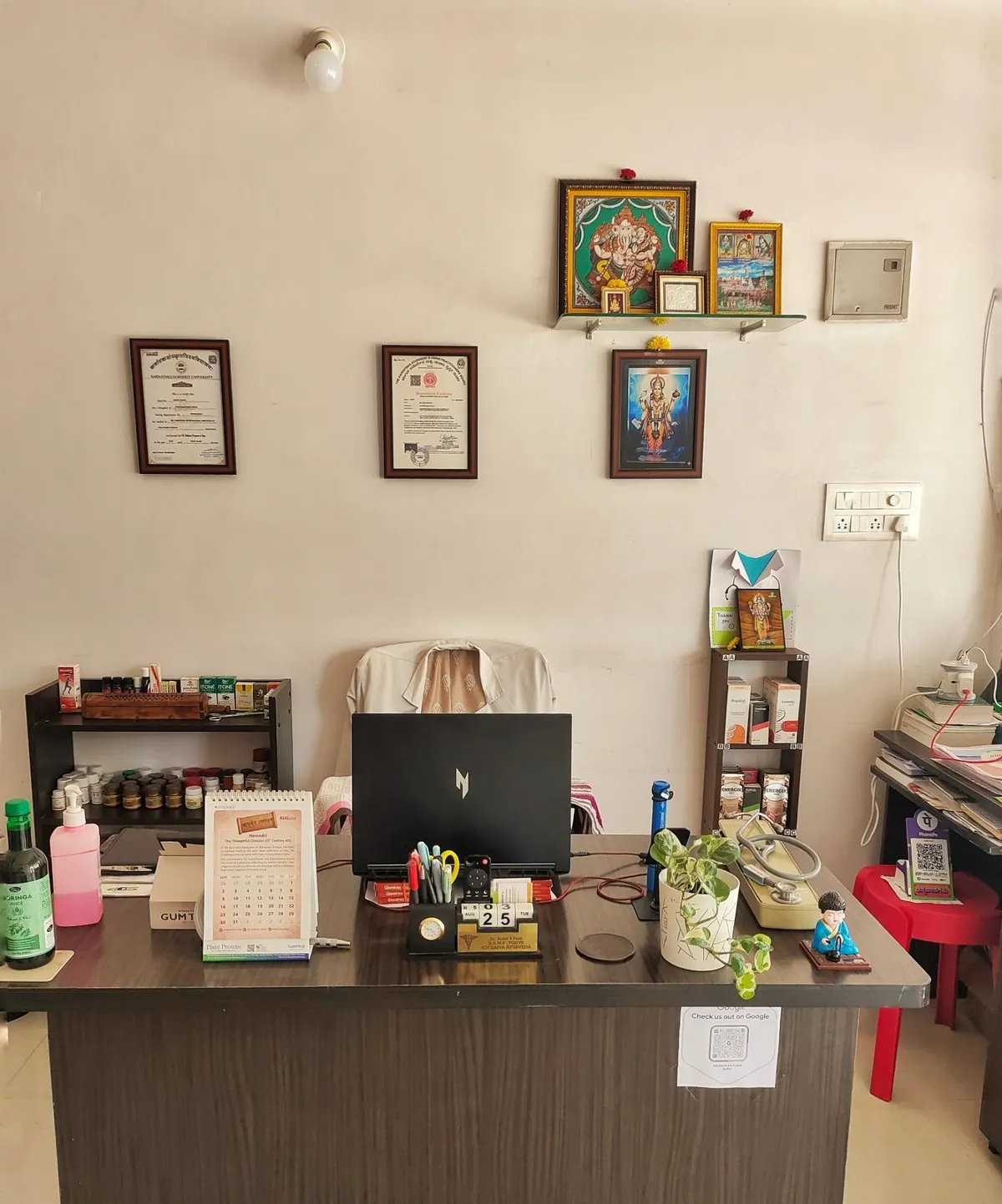 The consulting desk at Adi Daiva Ayurveda Clinic, with certificates and shrine above